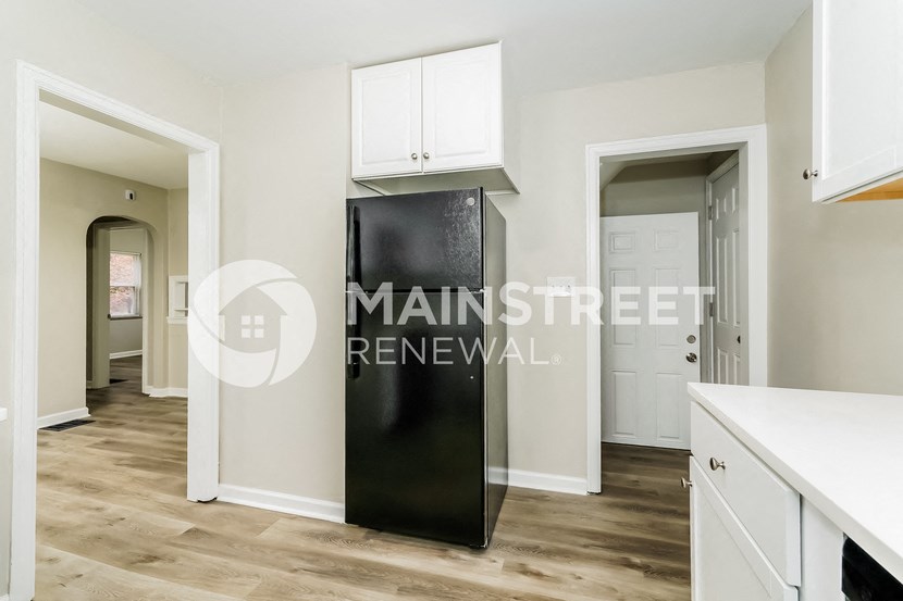 a renovated kitchen with white cabinets and a stainless steel refrigerator