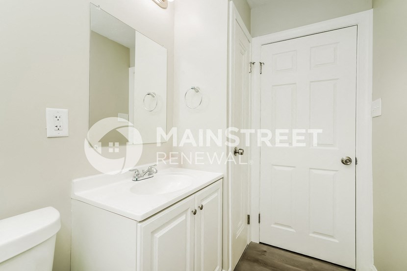 a white bathroom with a sink and a white door