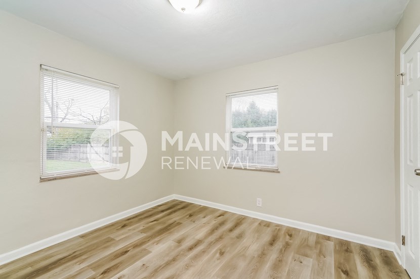 a bedroom with a hardwood floor and white walls