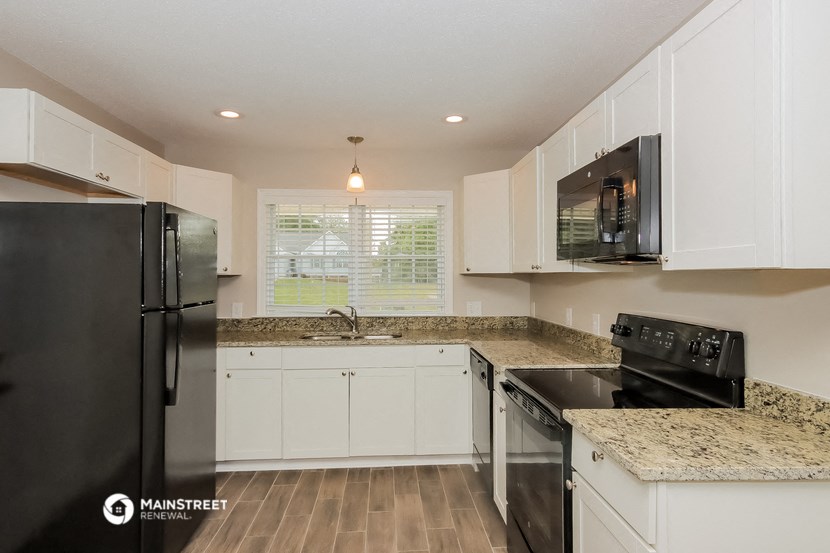 a kitchen with white cabinets and black appliances and granite counter tops