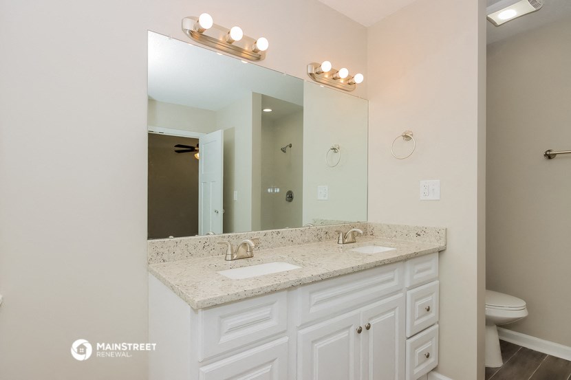 the master bathroom has a large vanity with two sinks and a large mirror