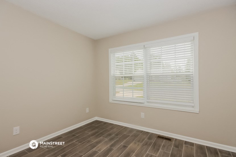 the spacious living room with a large window and wood flooring