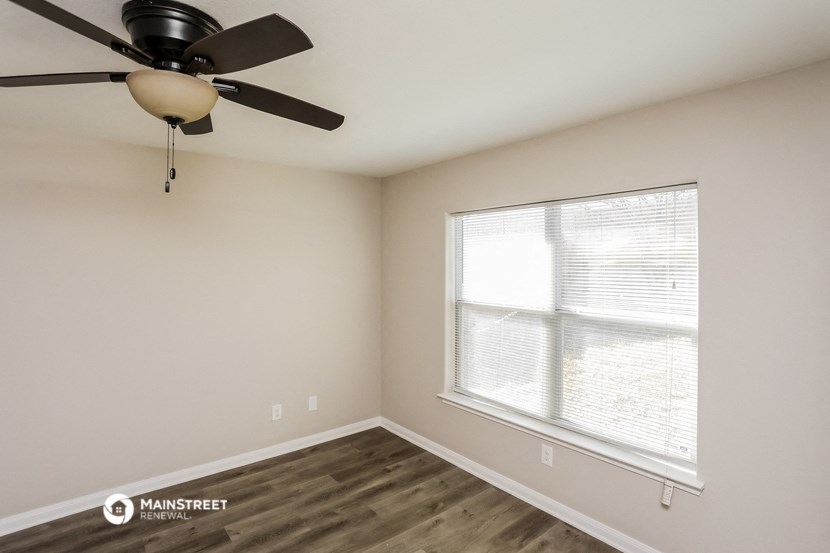 a bedroom with a large window and a ceiling fan
