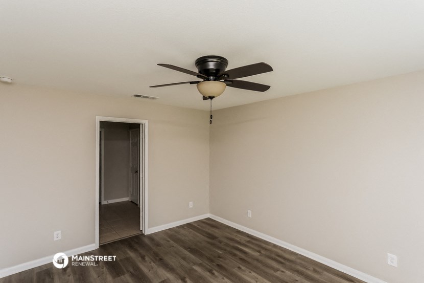 a living room with a ceiling fan and a door to a hallway