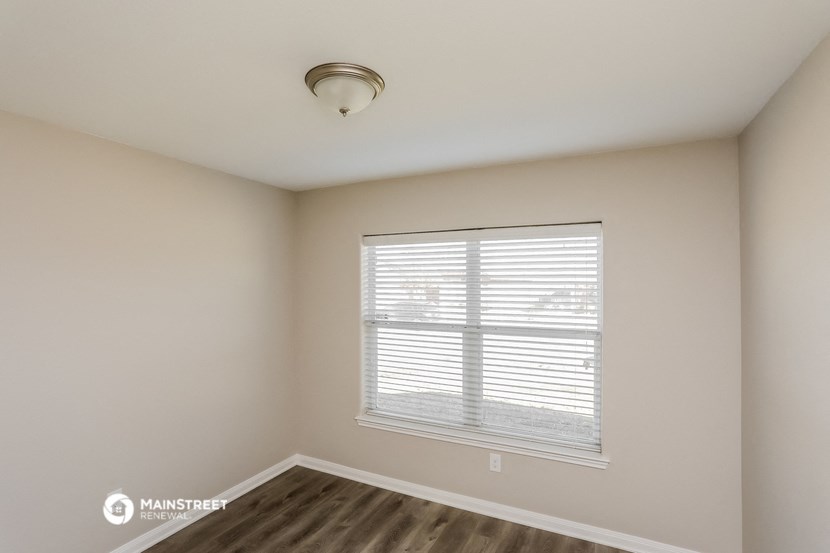 the spacious living room with a large window and wood flooring