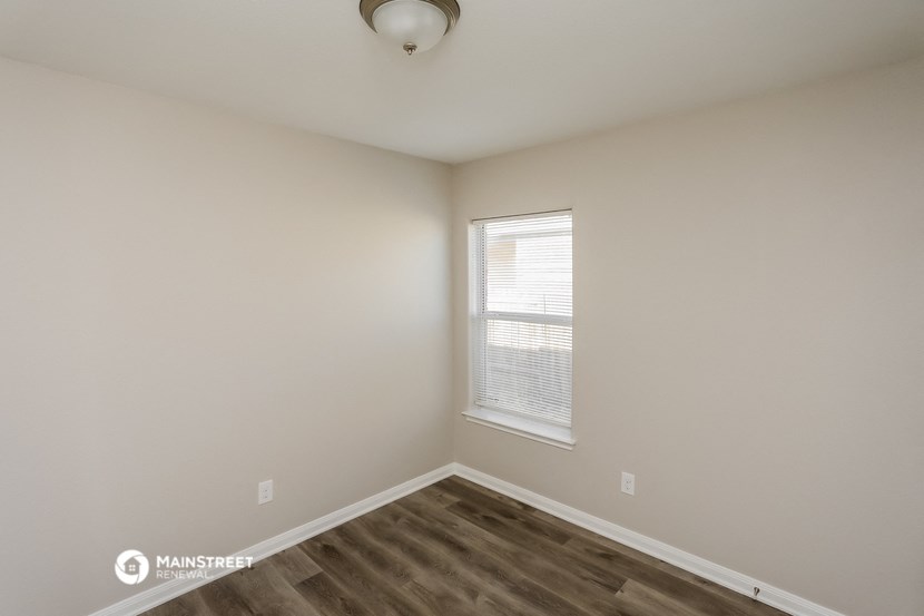 the interior of a bedroom with wood flooring and a window