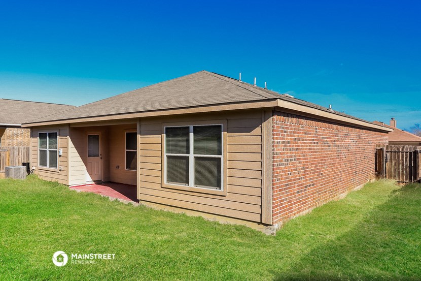 a small brown brick house with a yard and grass