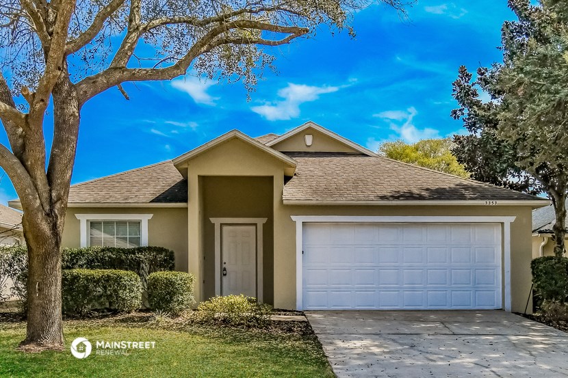 a beige house with a garage and a tree