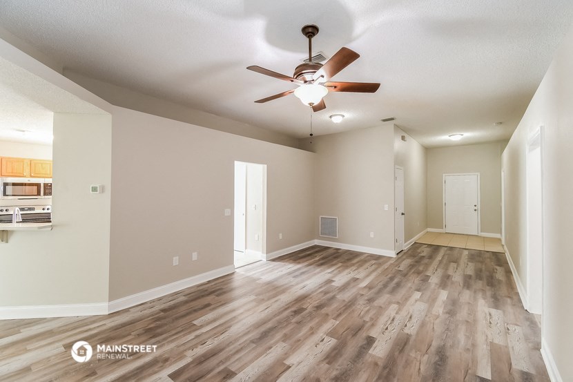 the spacious living room with hardwood floors and a ceiling fan