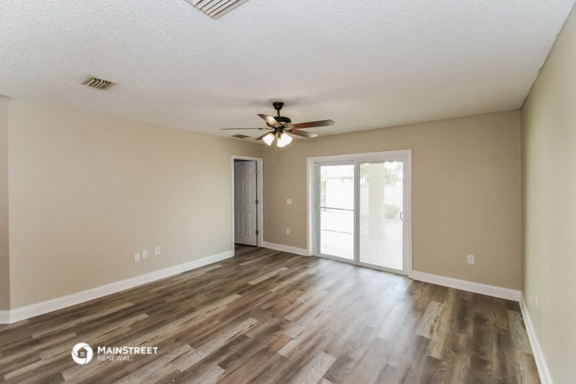 the spacious living room with wood flooring and a ceiling fan