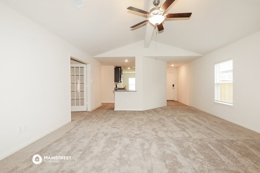 the living room and dining room of an empty house with a ceiling fan