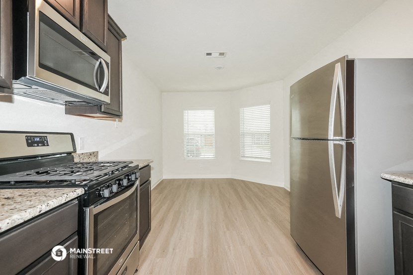 an empty kitchen with stainless steel appliances and wood flooring