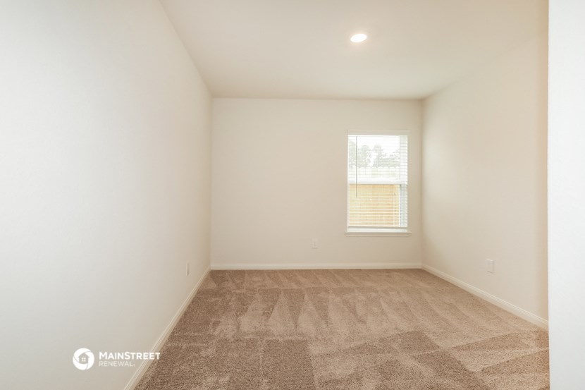 a spacious living room with carpet and a window