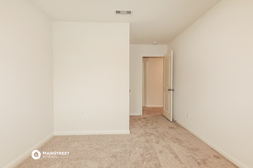 a bedroom with white walls and carpet and a door to a hallway