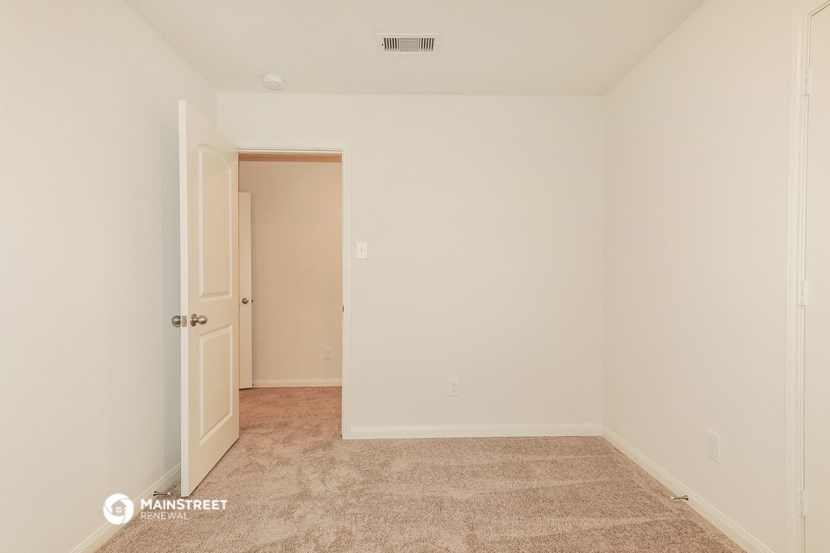 a bedroom with white walls and carpet and a door to a closet