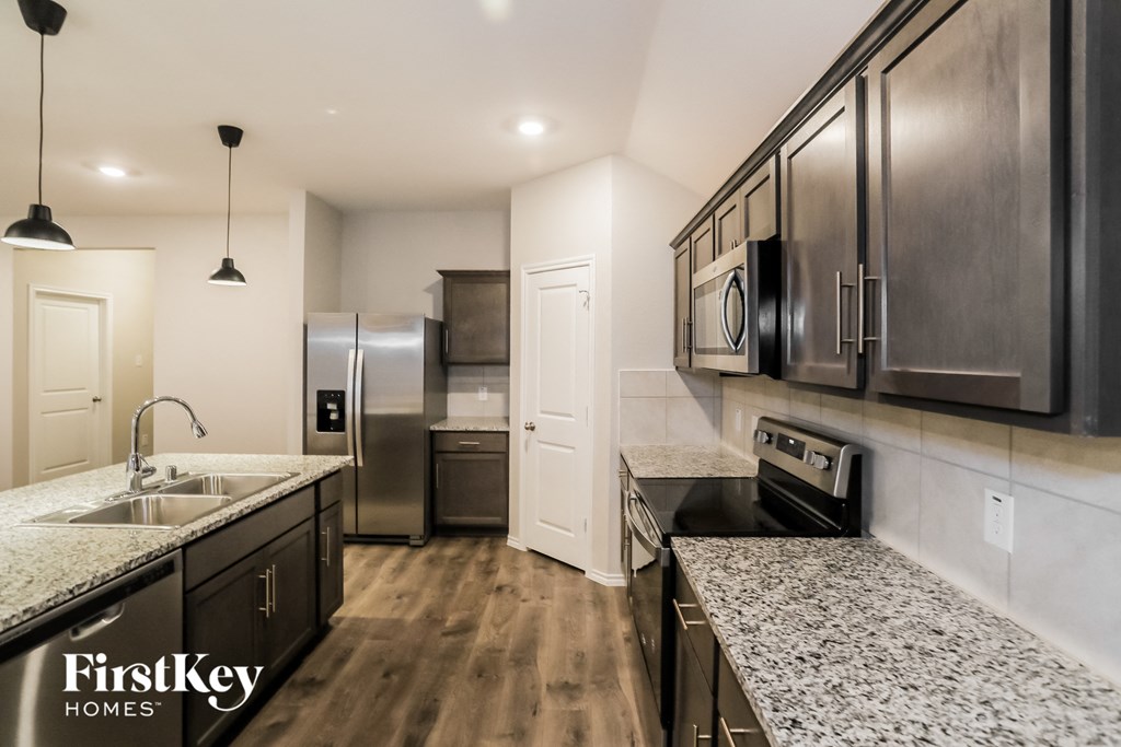 A kitchen with dark wood cabinets and a granite countertop.