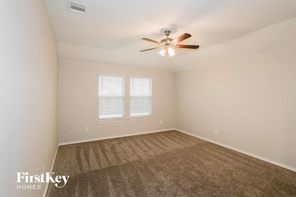 A room with a carpeted floor and a ceiling fan.