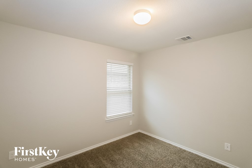 A room with a window and a carpeted floor.