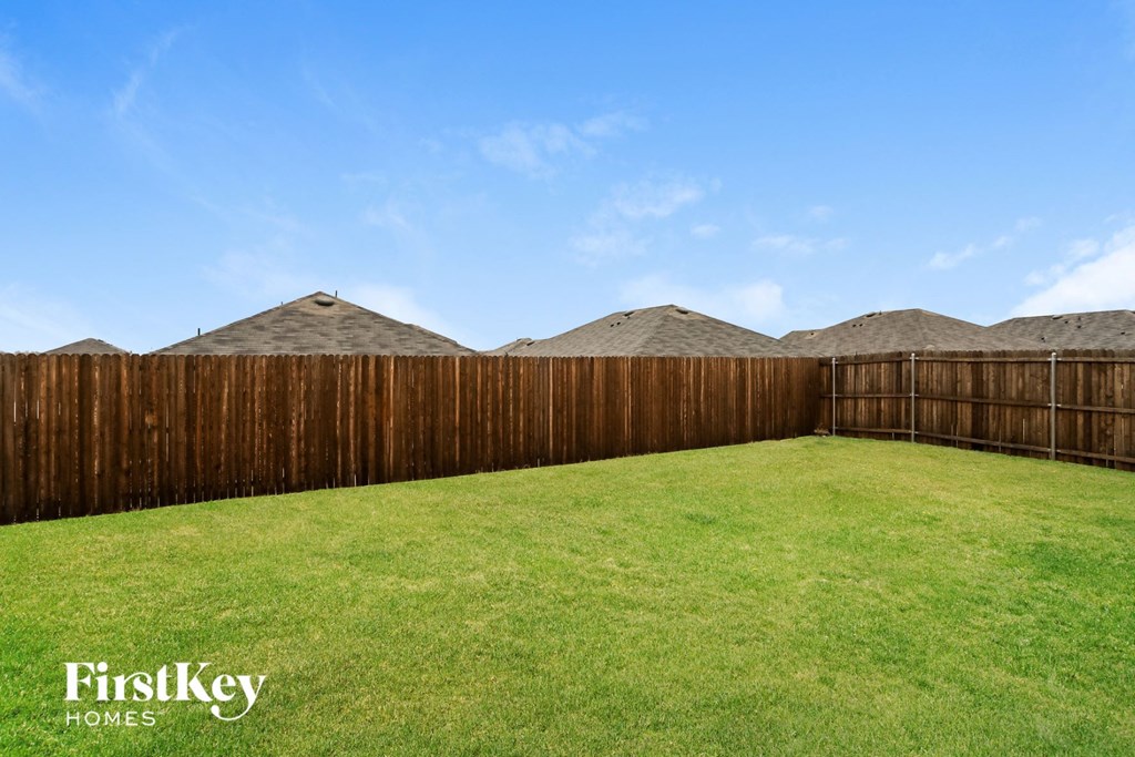 A backyard with a wooden fence and a green lawn.