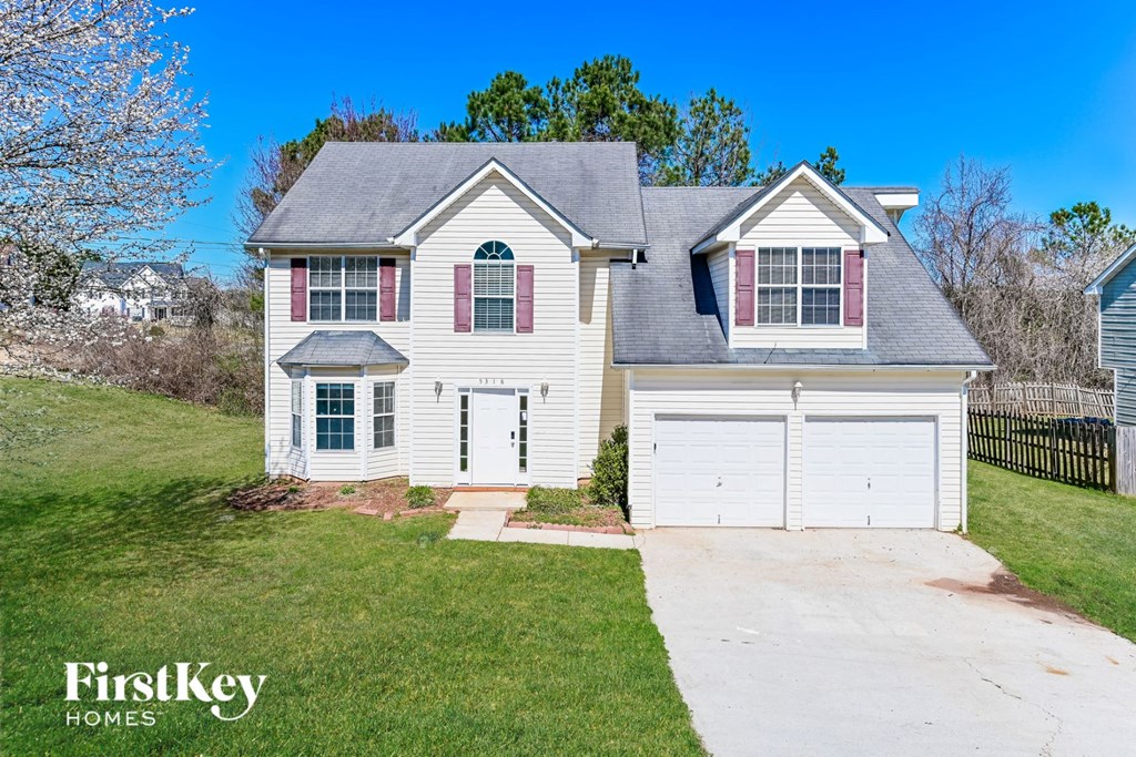 a white house with a white garage and a green lawn