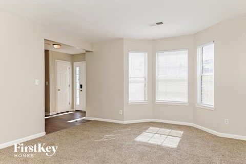a living room with three windows and a carpet