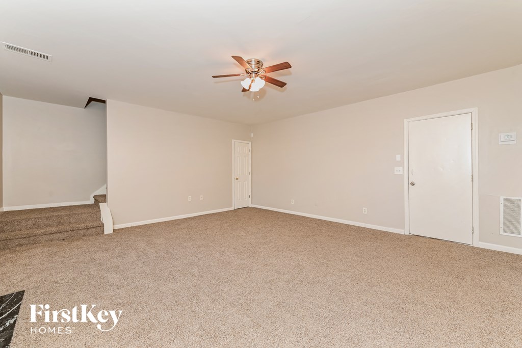 an empty living room with a ceiling fan