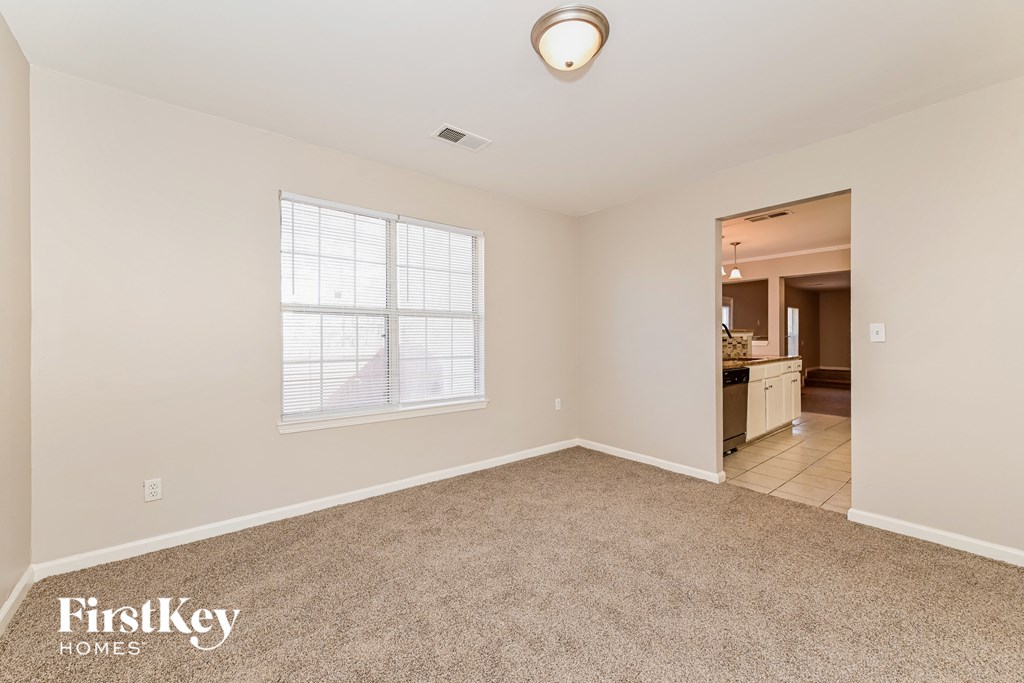 a spacious living room with carpeting and a large window