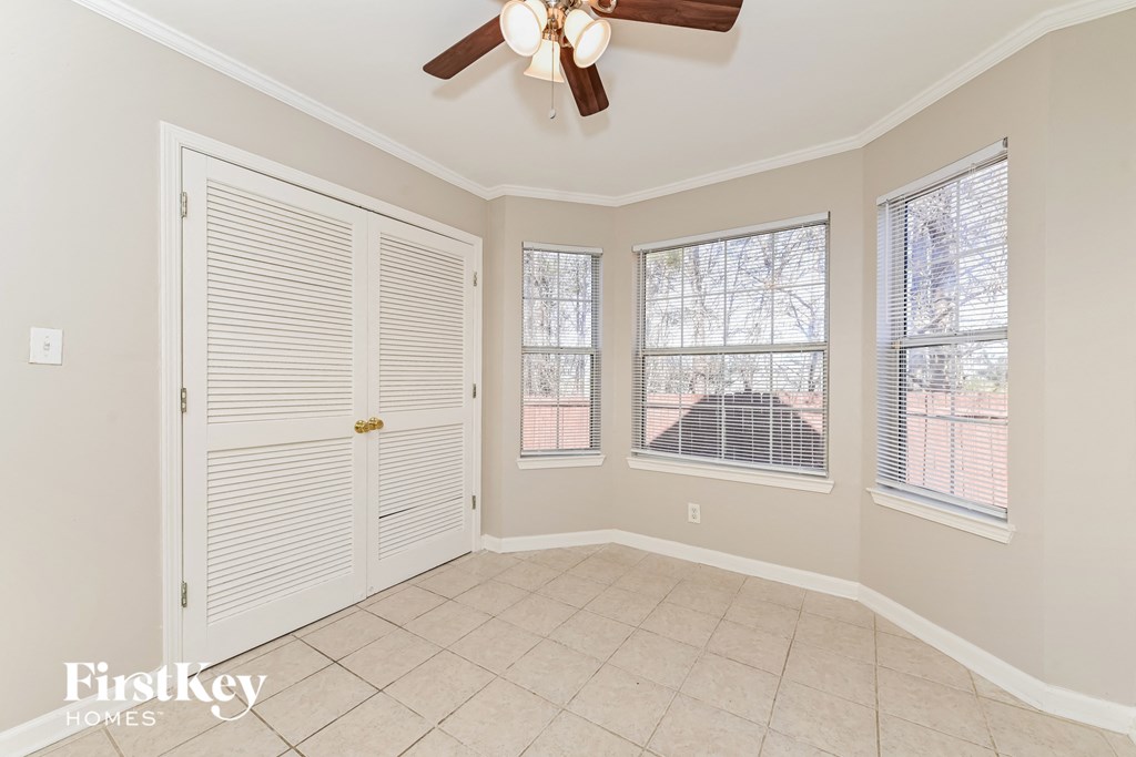 an empty living room with a ceiling fan and three windows