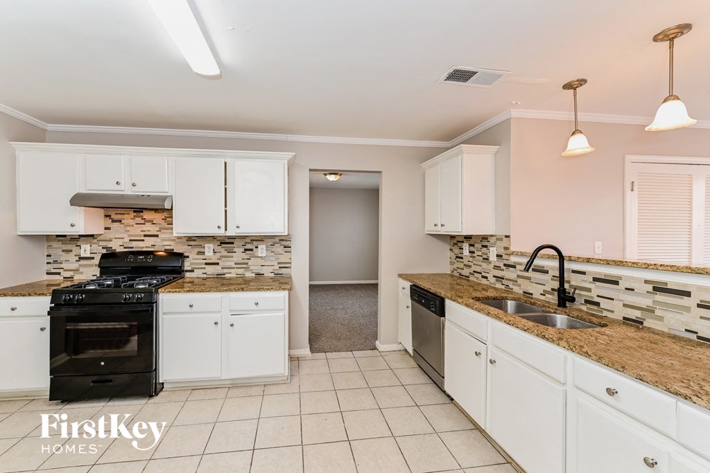 a kitchen with white cabinets and granite counter tops and a black stove