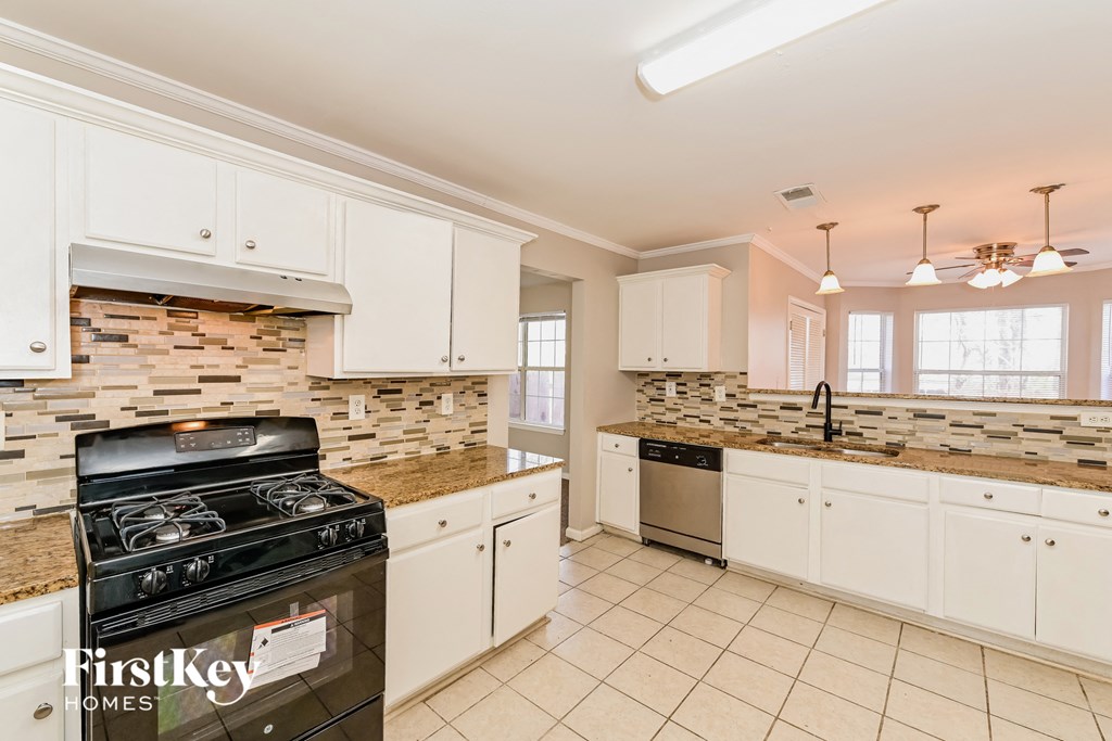 a kitchen with white cabinets and a stove and a sink