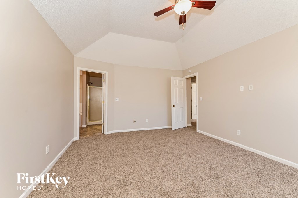 a spacious living room with carpet and a ceiling fan