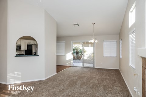 a living room with a rug and a door to a kitchen