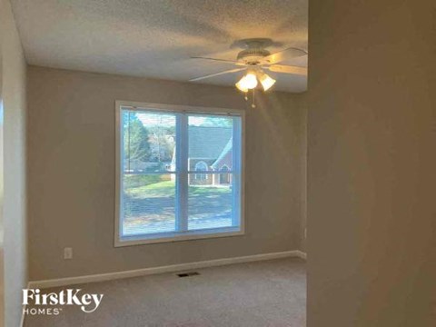 an empty bedroom with a ceiling fan and a window