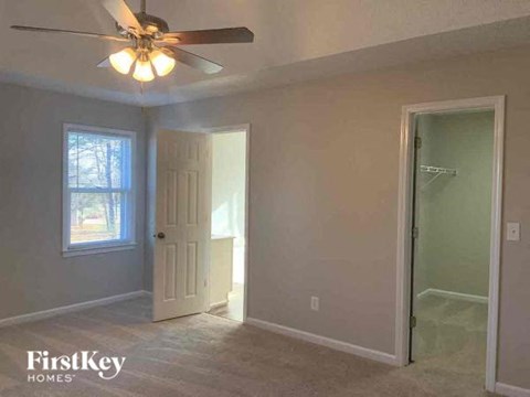 an empty bedroom with a ceiling fan and a door