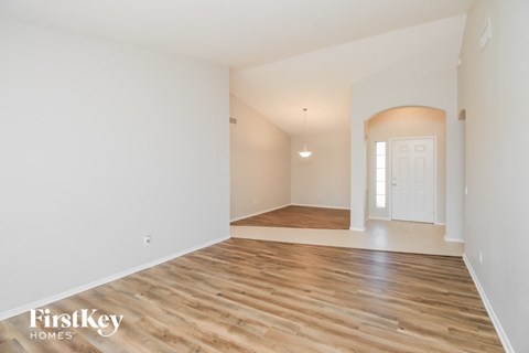 the living room and dining room with white walls and wood flooring