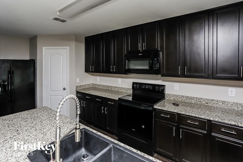 A kitchen with black cabinets and a granite countertop.