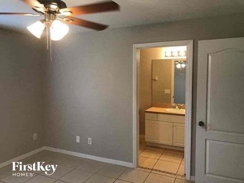 a bedroom with a ceiling fan and a bathroom with a sink