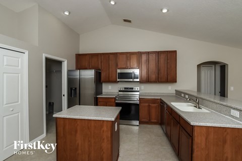 A kitchen with wooden cabinets and a stainless steel refrigerator.