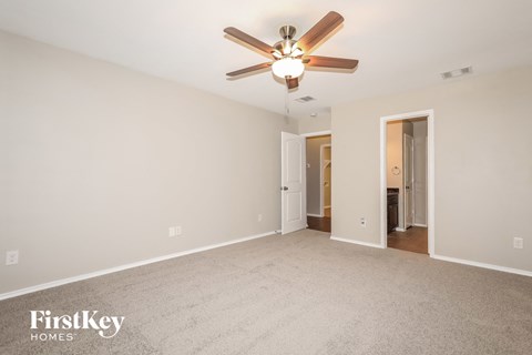 a spacious living room with carpet and a ceiling fan