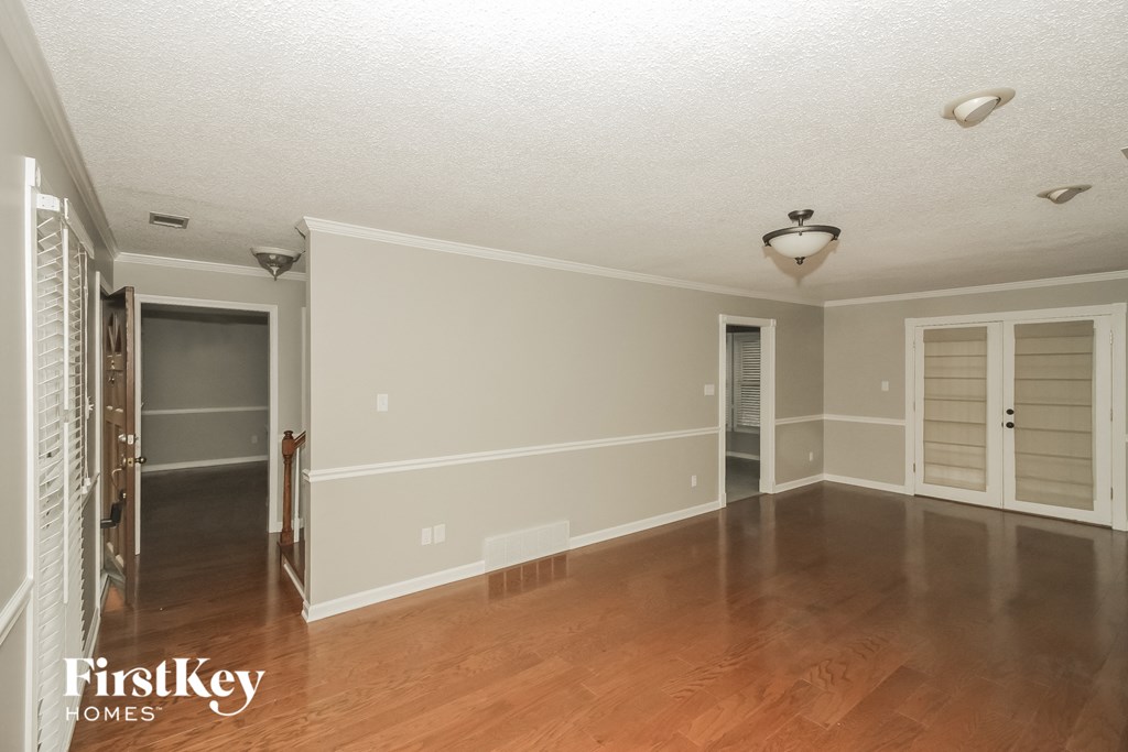 an empty living room with a hard wood floor and white walls