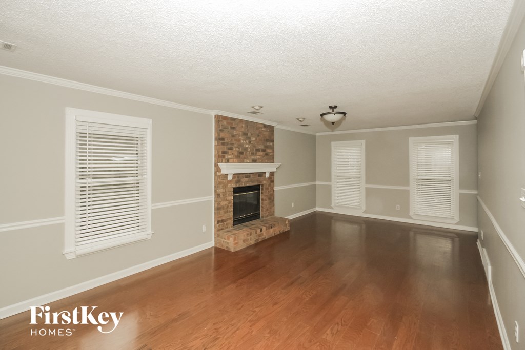 the living room of a house with a fireplace and wooden floors