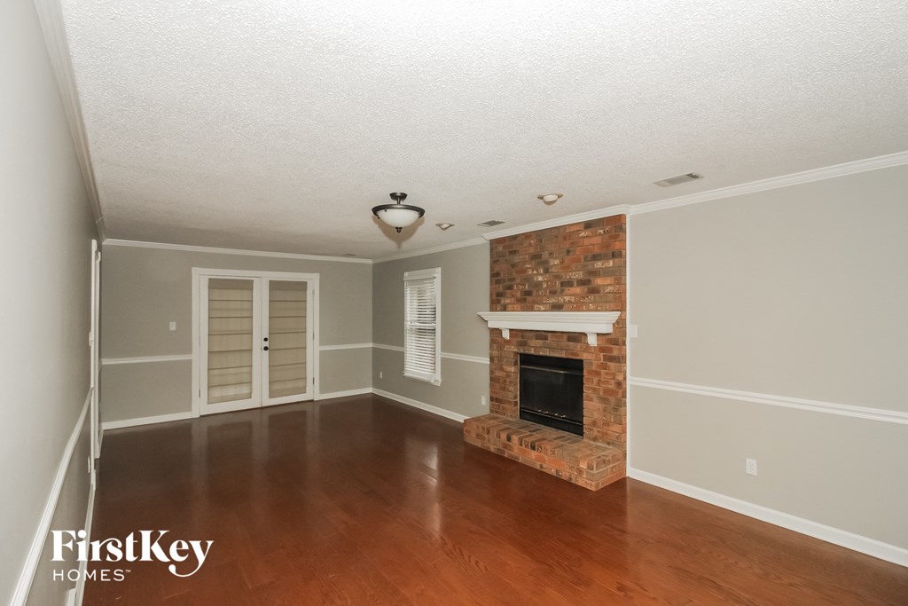 a living room with a brick fireplace and wooden floors