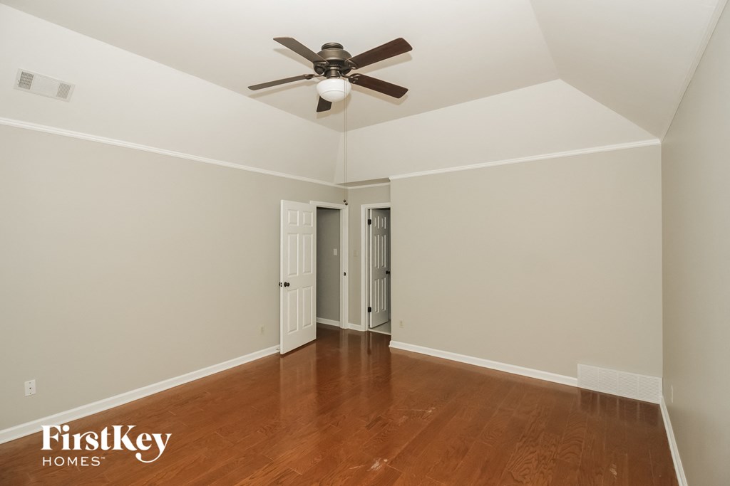 a bedroom with a ceiling fan and wood floors