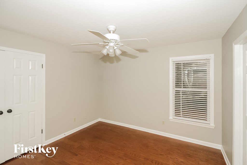 a bedroom with a wood floor and a ceiling fan