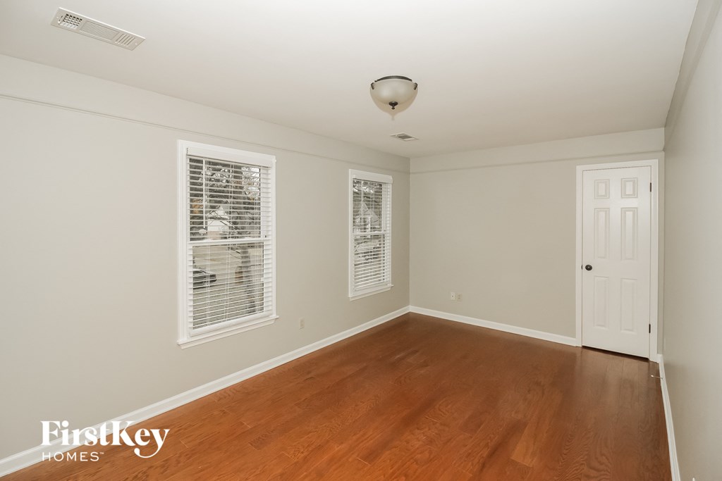 a bedroom with wood floors and white walls and a white door