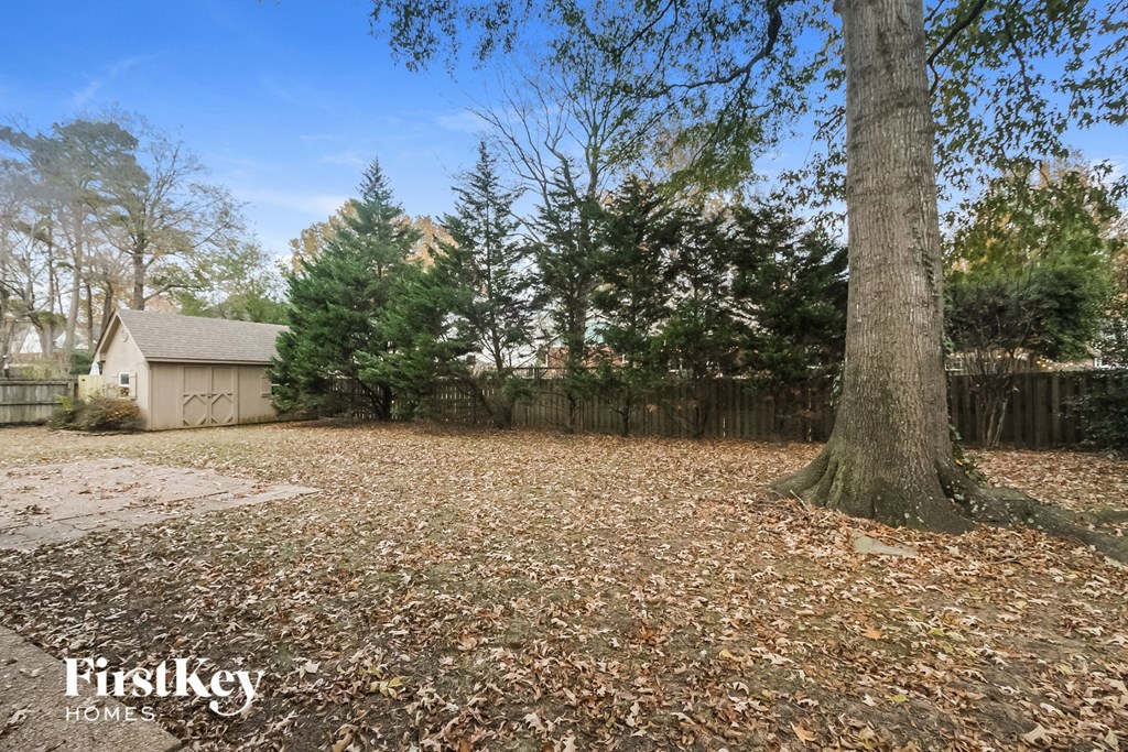 a yard with a tree and a house in the background