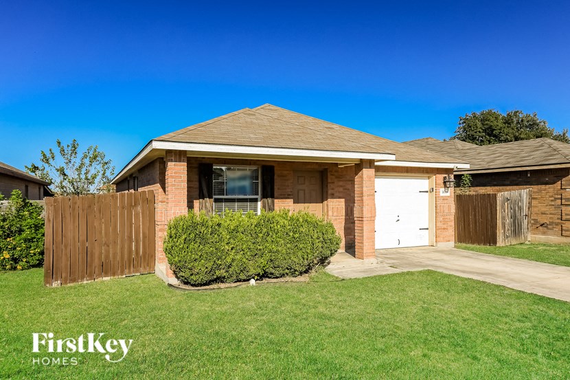 a small brick house with a wooden fence and a lawn