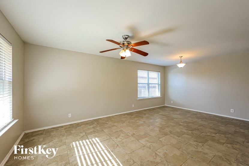 the spacious living room has a ceiling fan and tile flooring