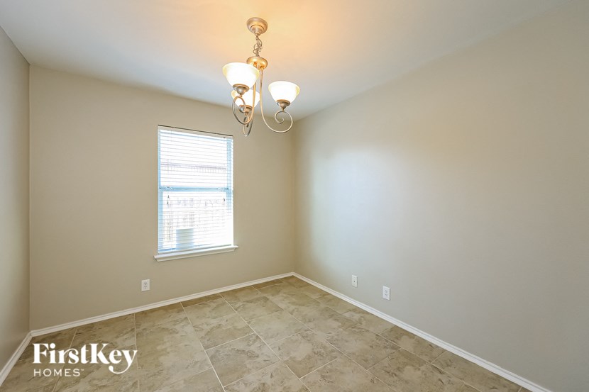 a empty dining room with a window and a chandelier