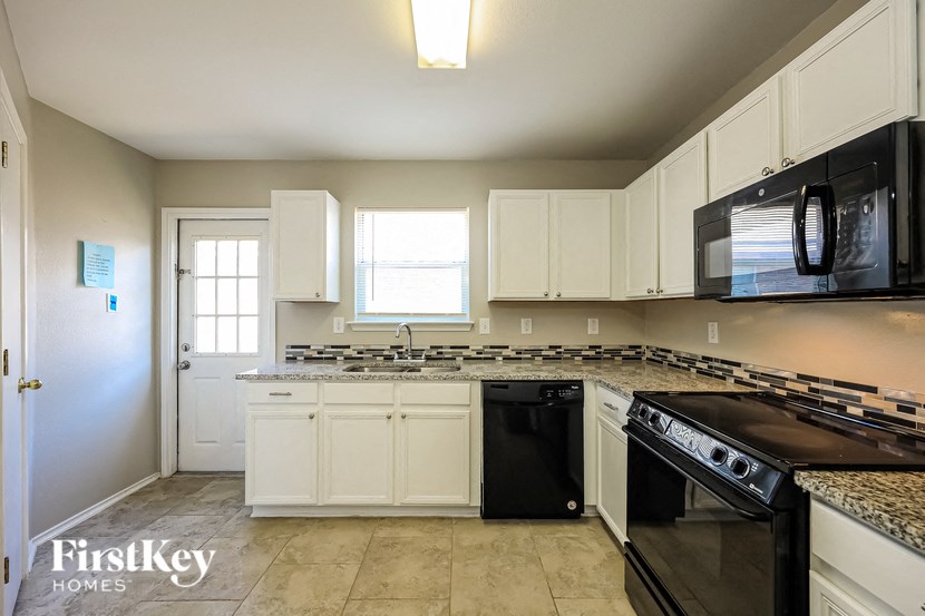 a kitchen with white cabinets and black appliances